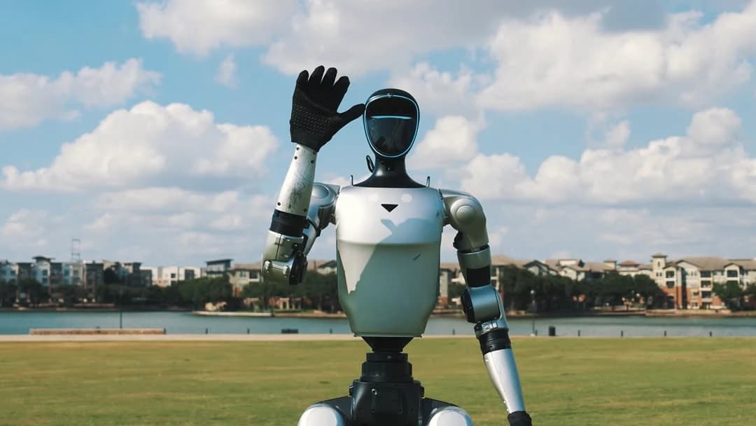 Humanoid robot waving outdoors beside a lake.