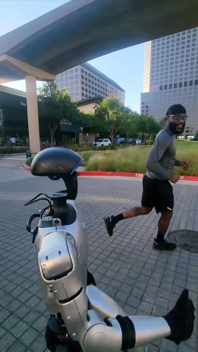 Humanoid robot jogging alongside a runner in the city.