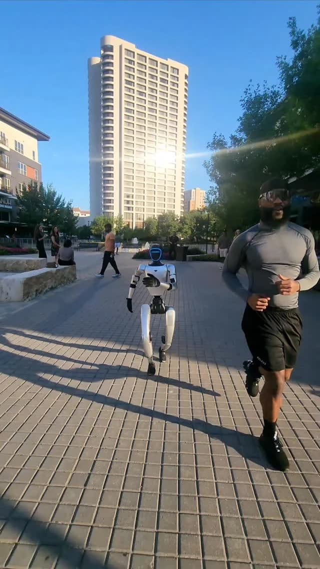 Humanoid robot walking alongside a runner outdoors.